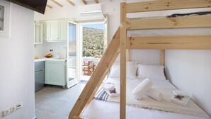 Ein Schlafzimmer mit einem Holzstockbett, einer kleinen Küchenzeile und Blick auf eine Berglandschaft.