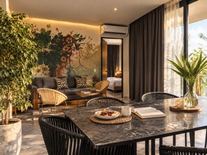 A modern living room with a dining area, featuring a sofa, chairs, a coffee table, and a dining table with a bowl of fruit and a book. - IIK: A Hip Condo-Hotel Oasis in Tulum Centro (Tulum)