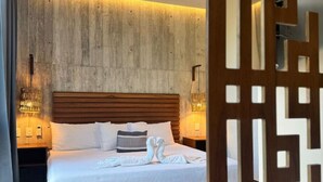 A modern hotel room with a wooden headboard, a neatly made bed, and a decorative wooden partition. - IIK: A Hip Condo-Hotel Oasis in Tulum Centro (Tulum)