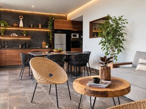 A modern kitchen with built-in appliances, a dining area with wicker chairs, and a round wooden coffee table. - IIK: A Hip Condo-Hotel Oasis in Tulum Centro (Tulum)