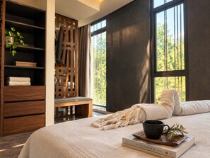 A bedroom with a large bed, a wooden wardrobe, a bench, and a window with a view of trees. - IIK: A Hip Condo-Hotel Oasis in Tulum Centro (Tulum)