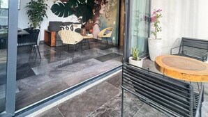 A modern interior with a glass door leading to a dining area with a round wooden table and black metal chairs. - IIK: A Hip Condo-Hotel Oasis in Tulum Centro (Tulum)