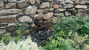 A stone wall with a small white pipe protruding from it. - Artistic barn: wood burning hottub, sauna and pizza oven  (Kent)