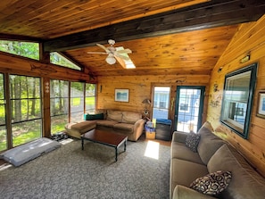 Relax in a cabin with a large sectional sofa, armchair, and expansive forest views.