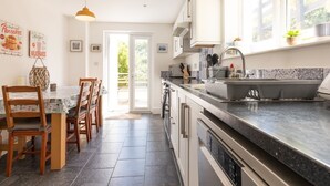 Une cuisine moderne dotée d’un plan de travail foncé, d’appareils électroménagers en acier inoxydable et d’une fenêtre donnant sur un paysage verdoyant.