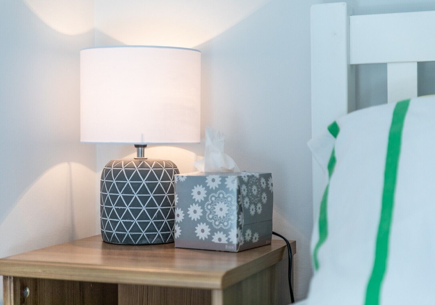 Une table de chevet avec une lampe et une boîte de mouchoirs.