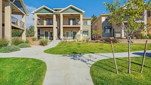 A multi-story residential building with a central courtyard, balconies, and a well-maintained lawn.