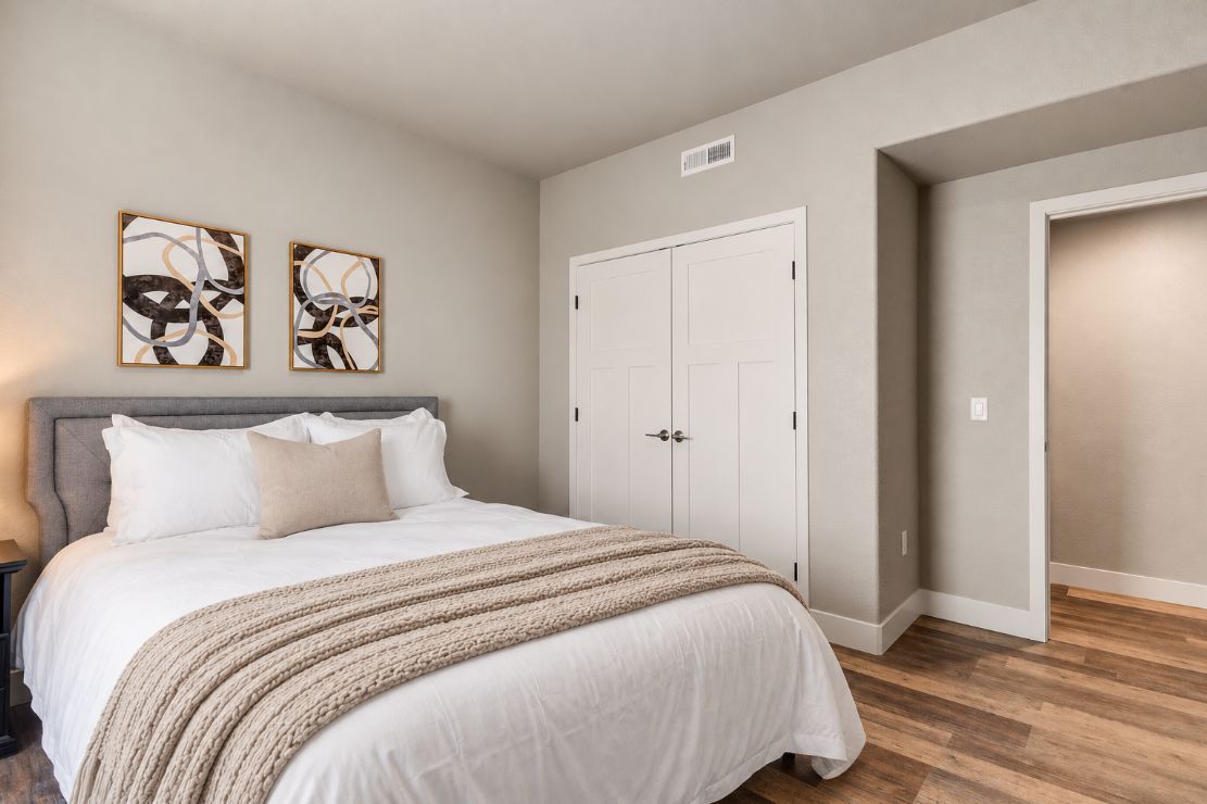 Une chambre à coucher comprenant un lit, deux œuvres d’art murales, une armoire et une porte.