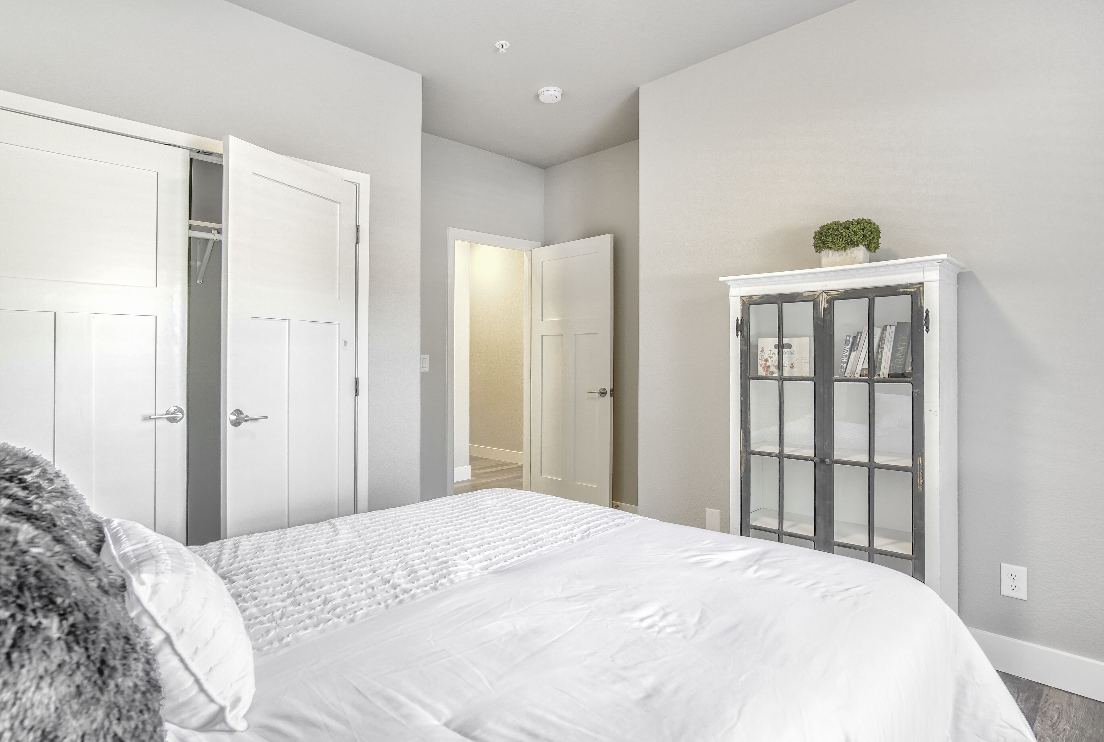 A bedroom with a bed, a wardrobe, and a door leading to another room.