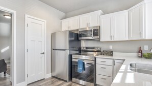 Una cocina moderna con armarios blancos, electrodomésticos de acero inoxidable y un horno empotrado.