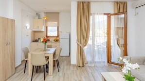 A modern kitchen with a dining area, a sofa, and a view of the outdoors. - Arvala Apartments  - Apartment with Balcony (Budva)