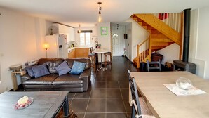 Un vaste espace de vie comprenant un canapé en cuir, une table à manger et une cuisine située à l’arrière-plan.