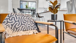 A modern living room with a sofa, a patterned throw, and a potted plant.