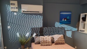 A bedroom with a bed, a potted plant, and a wall-mounted air conditioner. - Happiness and calm to enjoy a magnificent view  (Marseille)