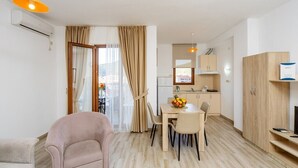 Un apartamento moderno con comedor, kitchenette y sala de estar con sofá y televisor.