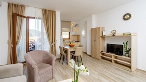 Una sala de estar moderna con un sofá, comedor, televisión y vistas a la ciudad.