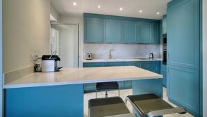 Een moderne keuken met turquoise kastjes, een marmeren aanrechtblad en een inbouwbank.