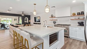 Una cocina moderna con una isla central, muebles blancos y electrodomésticos de acero inoxidable.