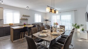 Una cocina moderna con comedor, que incluye una isla central, sillas de tonos oscuros e iluminación colgante.