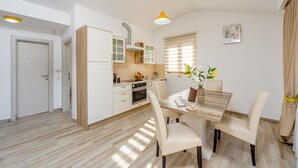 Eine moderne Küche mit weißen Schränken, einem eingebauten Backofen und einem Essbereich mit Holztisch und Stühlen.