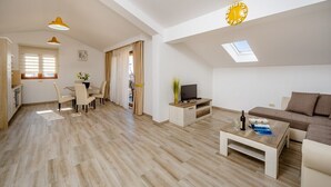 Ein geräumiger Wohnbereich mit Esstisch, Sofa und Fernseher.
