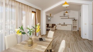 Ein modernes Wohnzimmer mit Essbereich, inklusive Holztisch, Laptop und Blumen in einer Vase.
