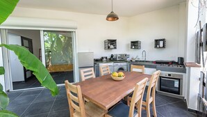 A modern kitchen with a dining table, chairs, and a fruit bowl.
