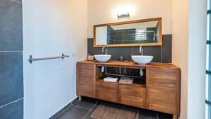 A modern bathroom with two vessel sinks, a wooden vanity, and a large mirror.