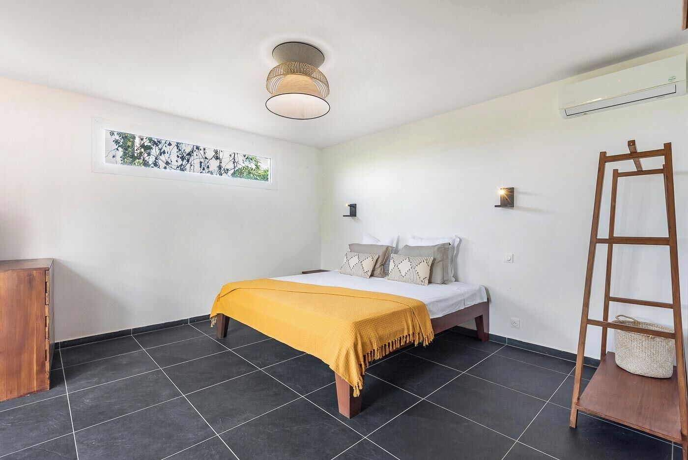 Une chambre avec un lit, une fenêtre donnant sur un beau paysage, un luminaire au plafond et une échelle en bois.