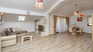 Een ruime woonkamer met een bank, salontafel, televisie en een eethoek.