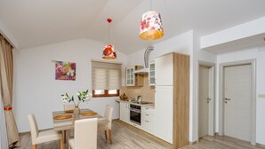 Een moderne keuken met witte kasten, een houten aanrecht en een eethoek met een tafel en stoelen.