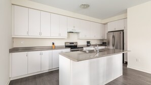 Une cuisine moderne avec des meubles blancs, un réfrigérateur en acier inoxydable et un îlot central.