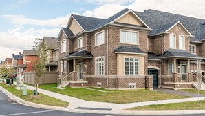 Une rangée de maisons de ville aux façades en briques, à plusieurs étages, avec des porches à l’avant.