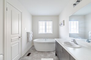 A modern bathroom with a freestanding bathtub, a vanity with a sink, and a large mirror.
