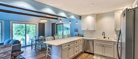 Una cocina moderna con una isla grande, armarios blancos y un comedor con mesa y sillas.