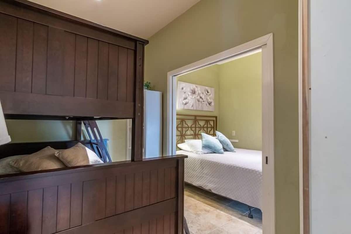 A bedroom with a wooden headboard, a bed with white bedding, and a painting on the wall.