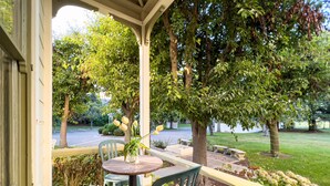 A covered patio with a table and chairs, surrounded by greenery and trees. - Chateau Coralini (Salinas)