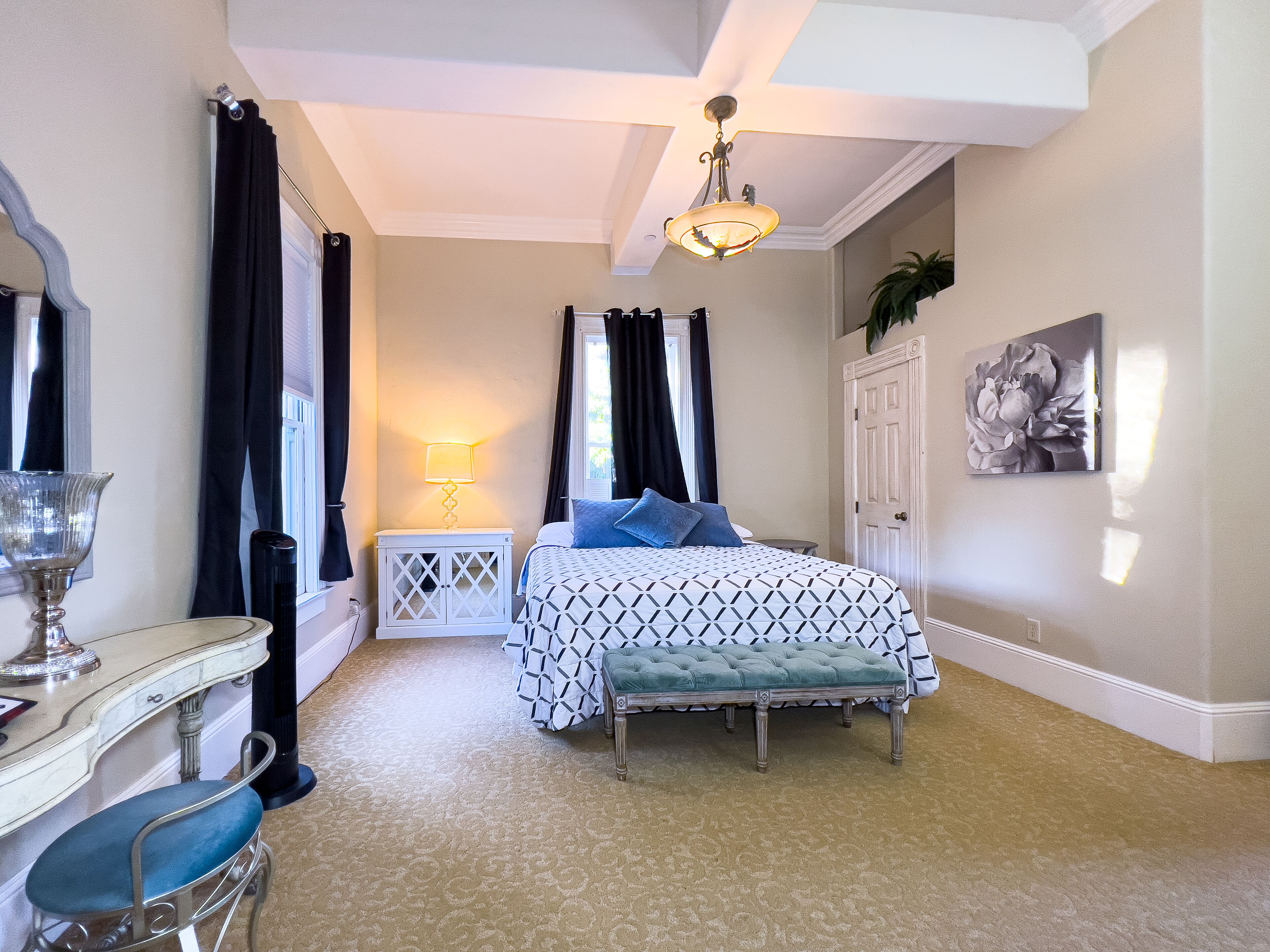 A bedroom with a bed, a bedside table, a lamp, a chair, and a door.