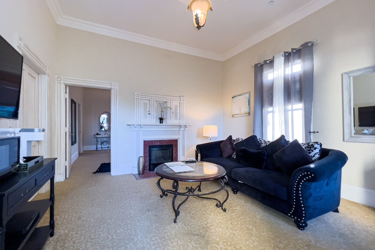 A living room with a fireplace, a blue sofa, a coffee table, and a television on a stand.