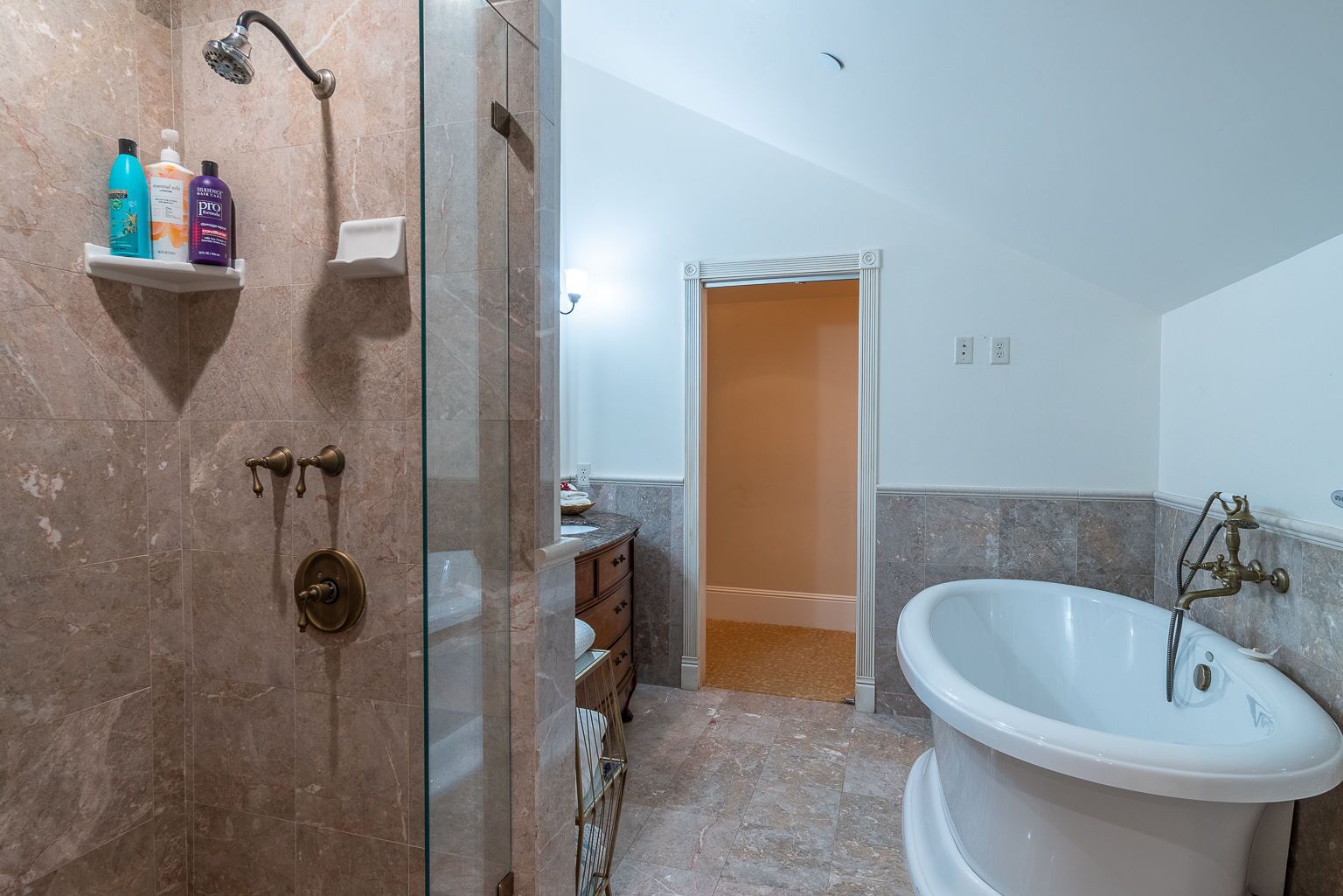 A bathroom with a bathtub, a shower, and a vanity with a mirror.