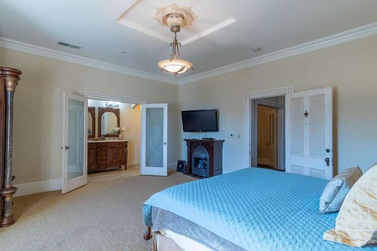 A bedroom with a large bed, a television, and a fireplace.