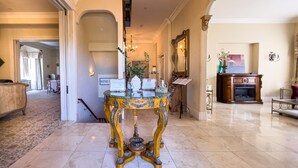 A grand lobby with a chandelier, a reception desk, and a fireplace. - Chateau Coralini (Salinas)