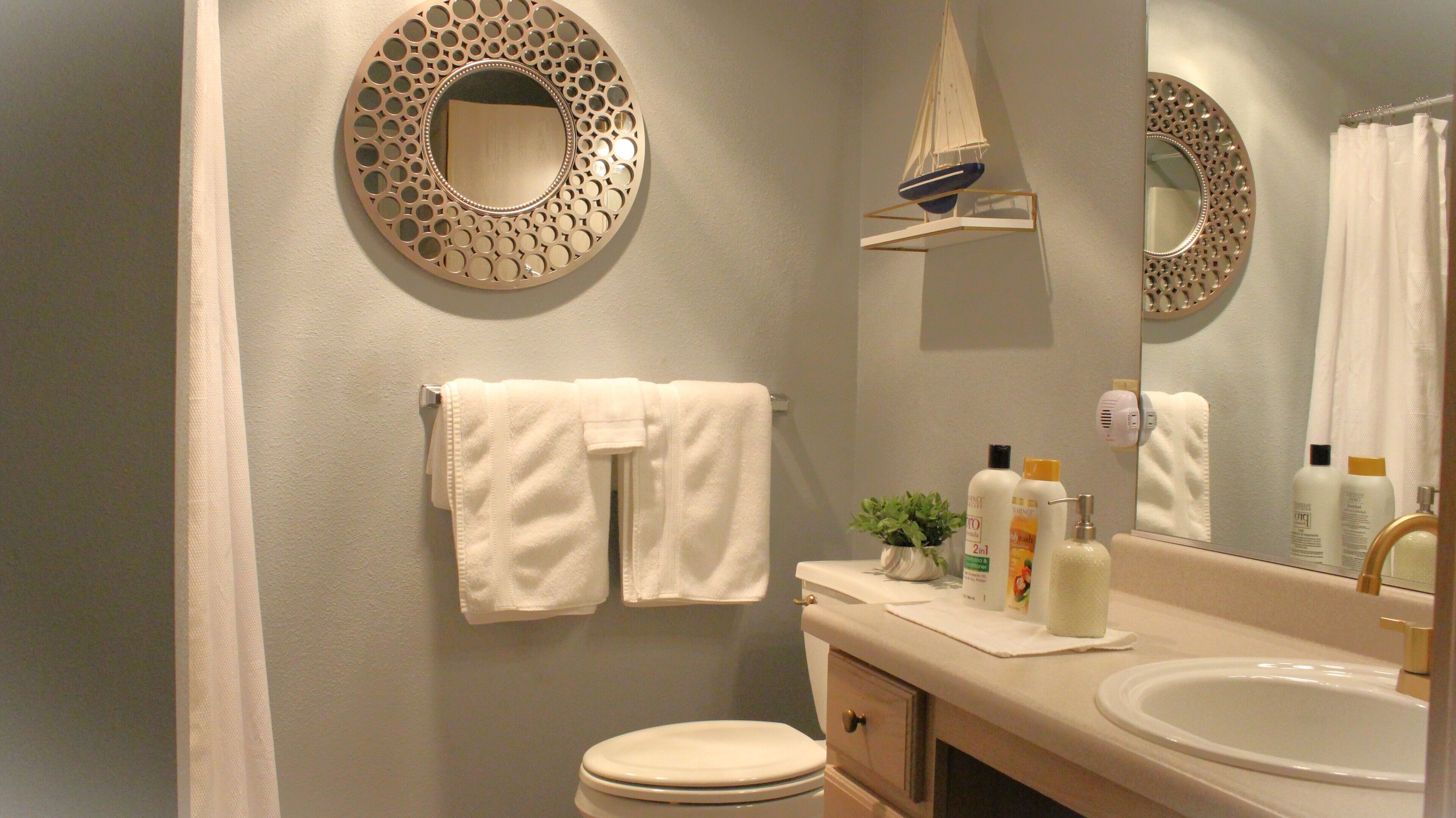 A bathroom with a toilet, sink, and two towels hanging on the wall.