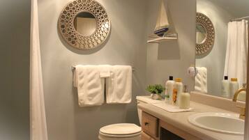 A bathroom with a toilet, sink, and two towels hanging on the wall.