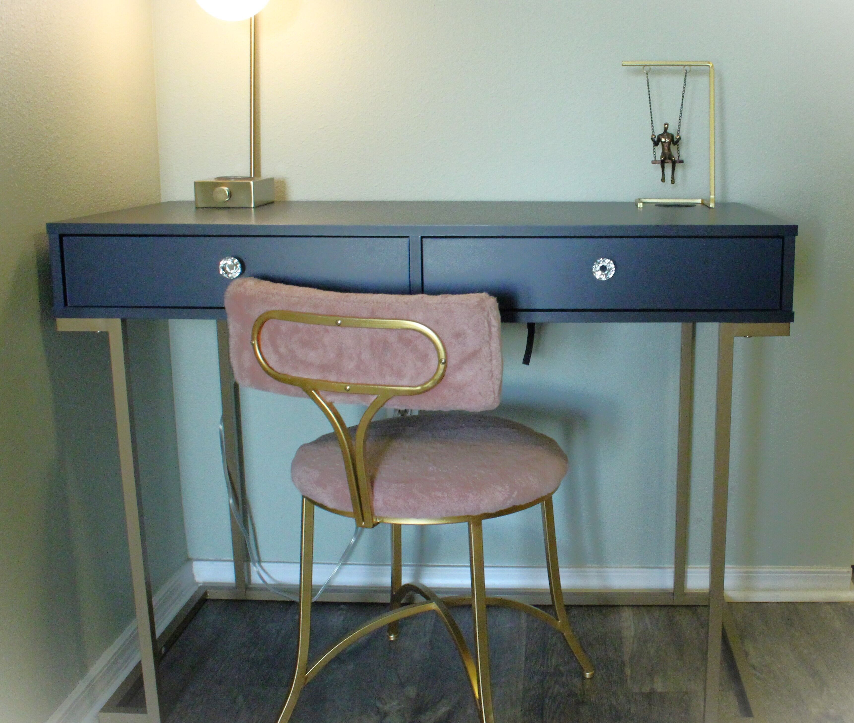 A desk with a chair, a lamp, and a small figurine on the desk.