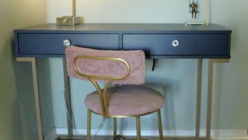 A desk with a chair, a lamp, and a small figurine on the desk.