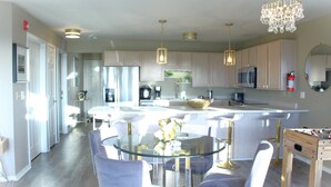 Een moderne keuken met witte kasten, een glazen eettafel en hanglampen.