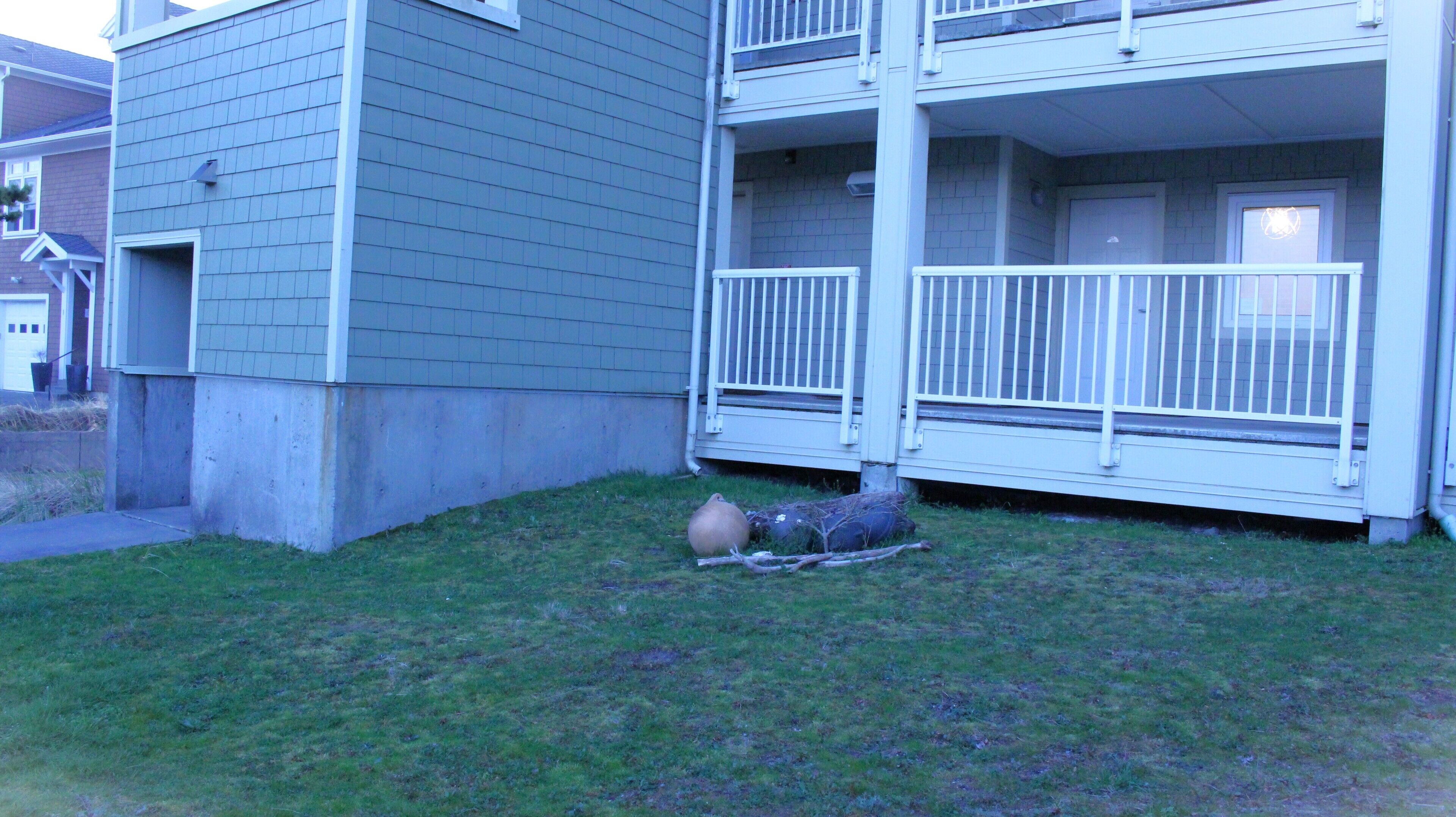 Ein zweistöckiges Gebäude mit Balkon und kleinem Garten.