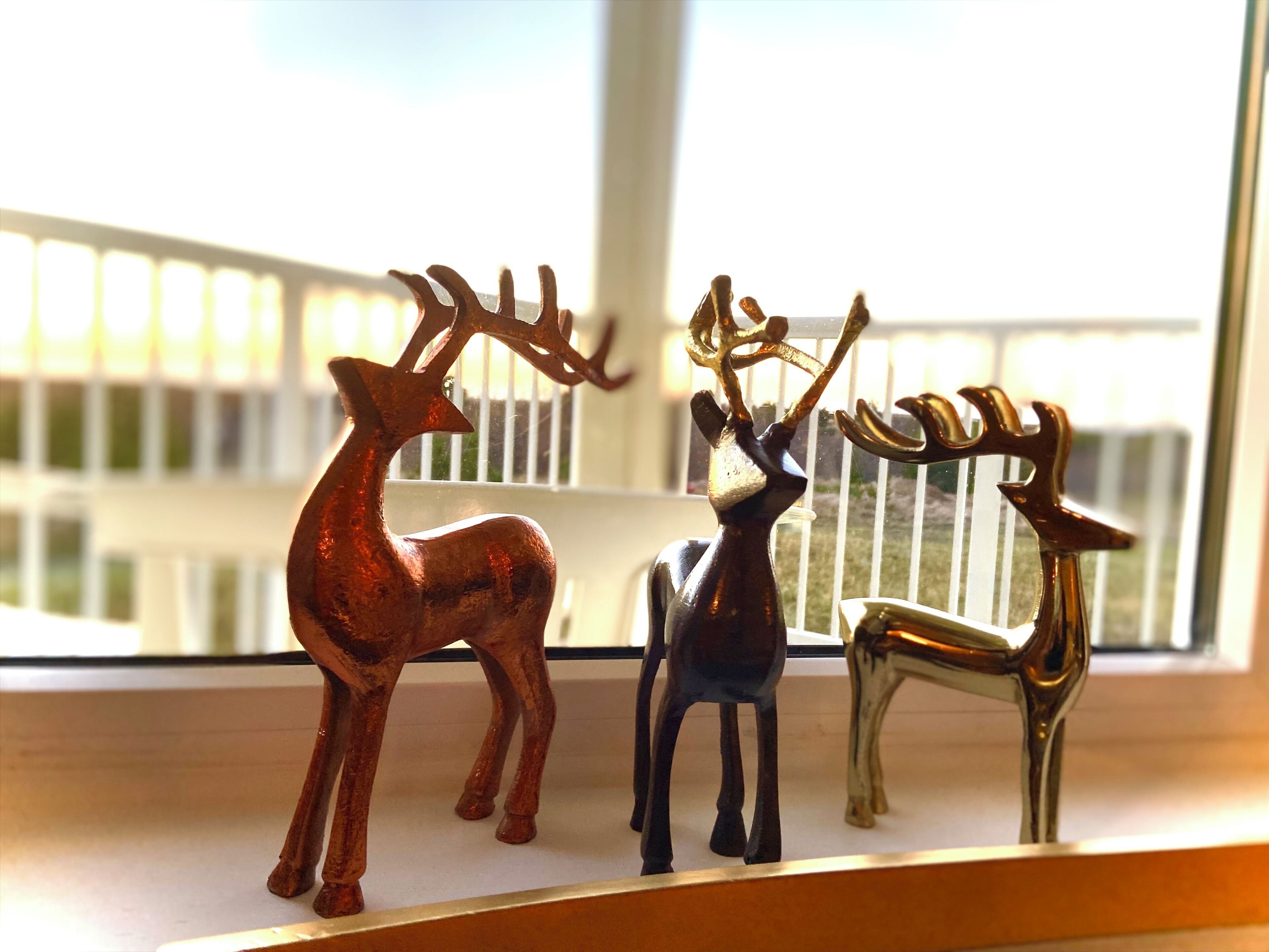 Three deer figurines on a windowsill.