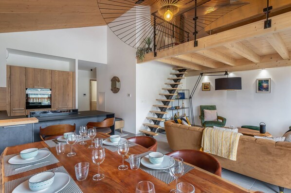 Une cuisine moderne avec des meubles en bois, une table à manger dressée avec des assiettes et des verres, et un escalier menant à l’étage supérieur.